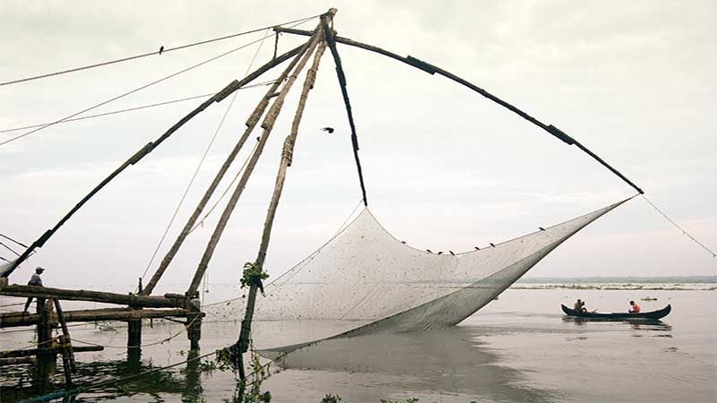 Blog Ambiental • Estrutura de pesca tradicional em um rio, com pescadores em um barco ao fundo.