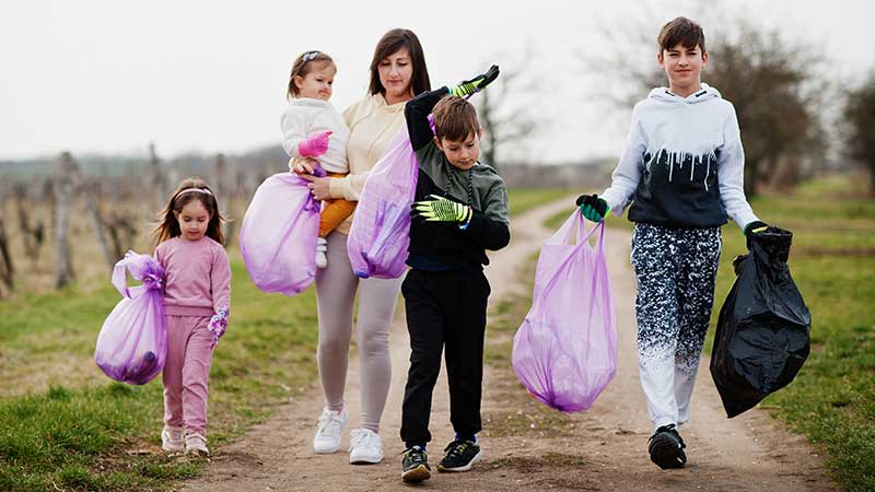 Família com crianças recolhendo lixo em área rural, destacando ações de conscientização no Blog Ambiental