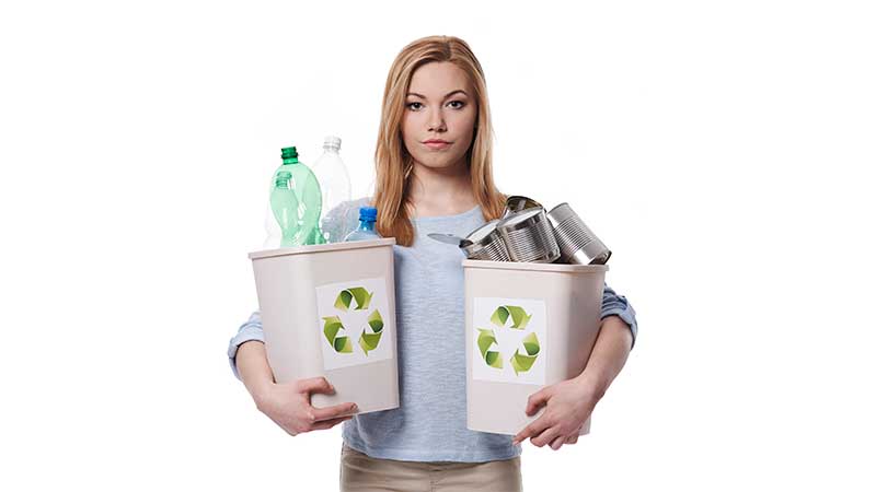 Mulher segurando dois recipientes com plásticos e metais recicláveis, simbolizando coleta seletiva em casa