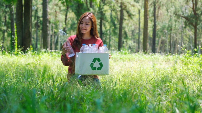 Blog Ambiental • Jovem mulher segurando plásticos para reciclagem em meio à natureza