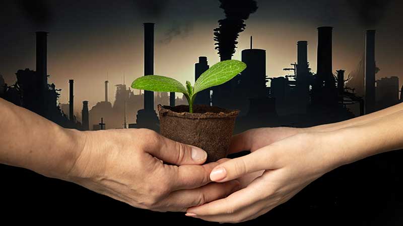 Mãos trocando muda verde com fundo de fábricas poluentes, representando a transição da indústria para a sustentabilidade.
