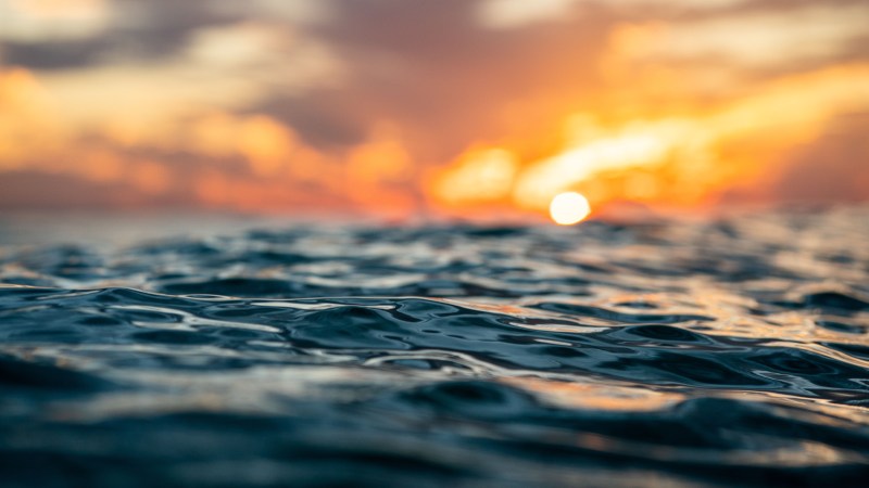 Blog Ambiental • Superfície do oceano ao entardecer com o sol se pondo no horizonte.