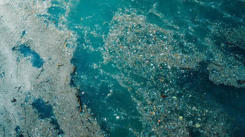Blog Ambiental • Vista aérea de lixo flutuante e microplásticos acumulados no oceano.