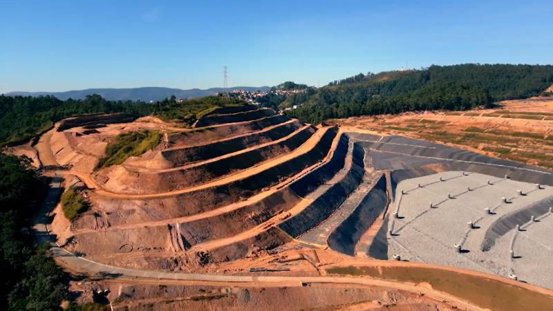 Aterro sanitário em camadas com vista aérea, mostrando etapas de engenharia e contenção ambiental — cena da série O Lixo Também É Seu.
