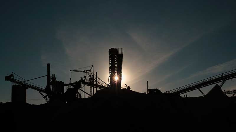 estrutura industrial em silhueta com o sol ao fundo, simbolizando os bastidores da economia circular e da indústria de reciclagem no Brasil • Blog Ambiental