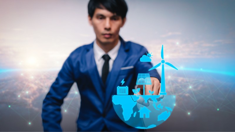 Blog Ambiental • Profissional interagindo com holograma de energias renováveis, incluindo solar, eólica e sistemas inteligentes.