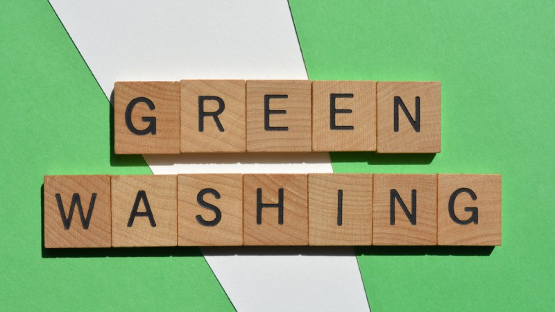 Blog Ambiental • Palavra greenwashing formada por blocos de madeira sobre fundo verde.